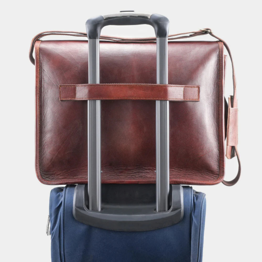 Leather messenger bag attached to rolling luggage for convenient business travel.