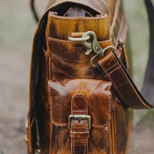 Close-up of premium full-grain leather and brass hardware on the Norwood messenger bag.