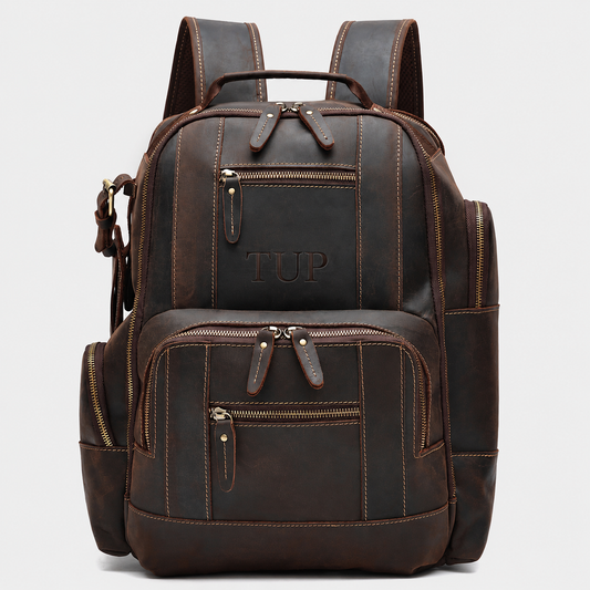 The Atlas full grain leather backpack in dark brown with multiple front organizer pockets and premium brass hardware