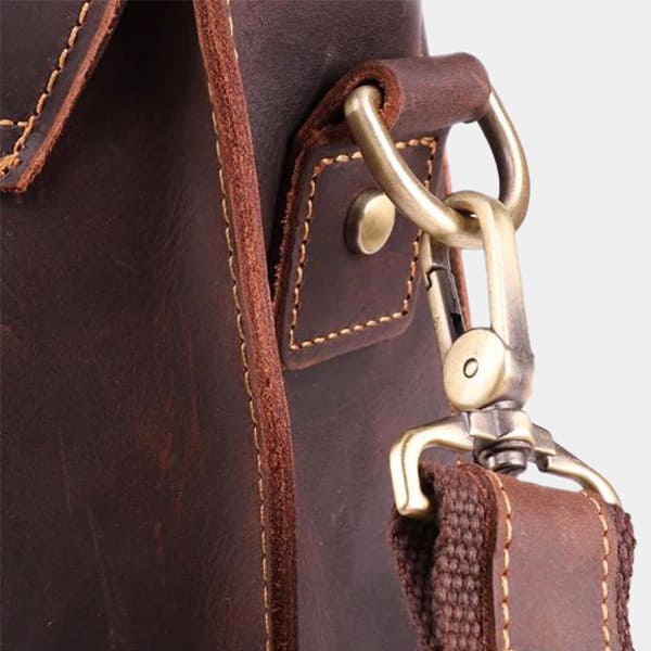 Close-up of a brown leather bag with gold hardware and strap.