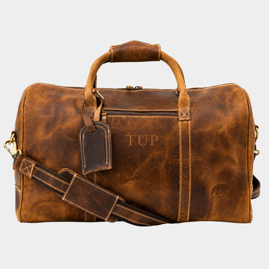The Overnighter 30L top grain leather duffle bag in vintage brown with adjustable shoulder strap and luggage tag